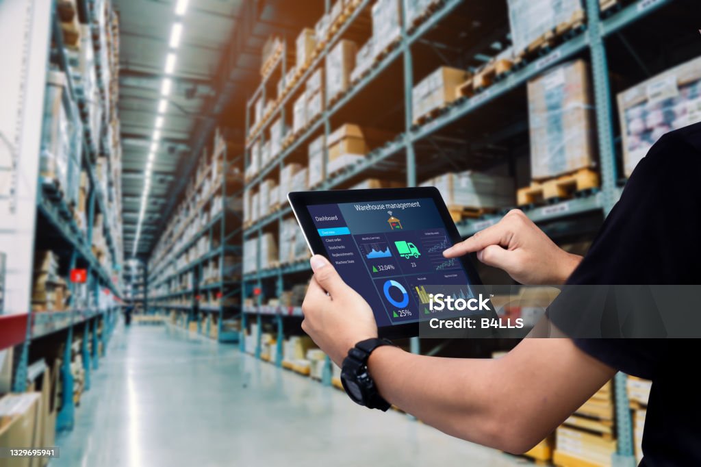 Worker hands holding tablet on blurred warehouse as background